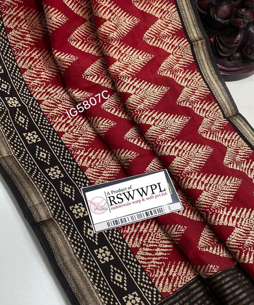 "Chic leaf print Dola silk saree with tassels, red with black, epitomizing elegance and style."